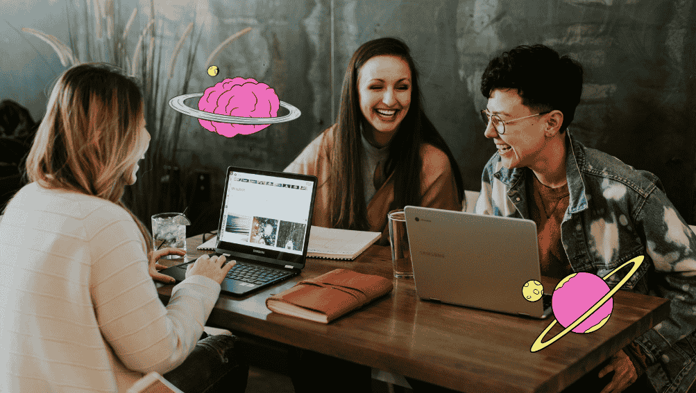 A team working on their laptops and laughing in a coffee shop together